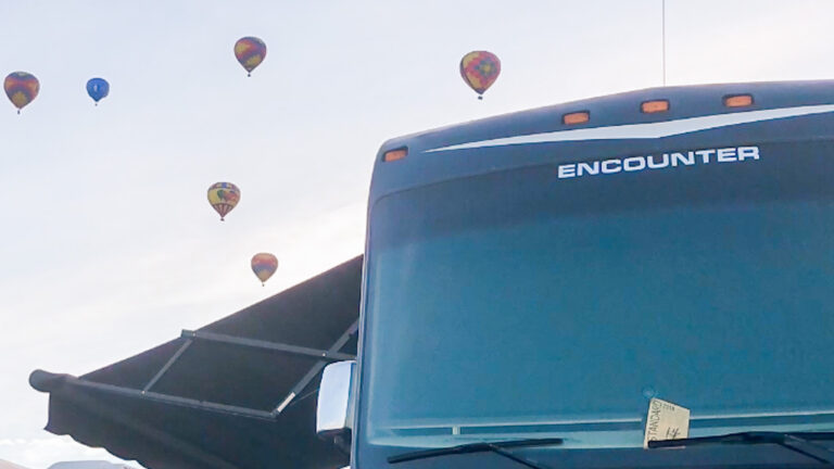 an RV awning with hot air balloons behind