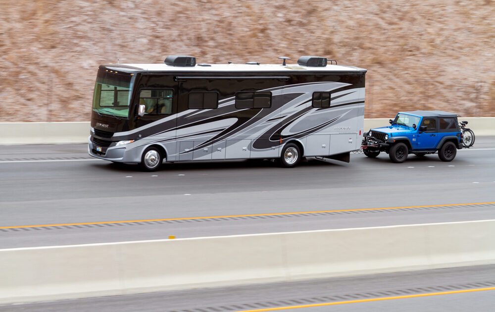 A large RV towing a smaller Jeep