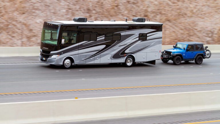 A large RV towing a smaller Jeep