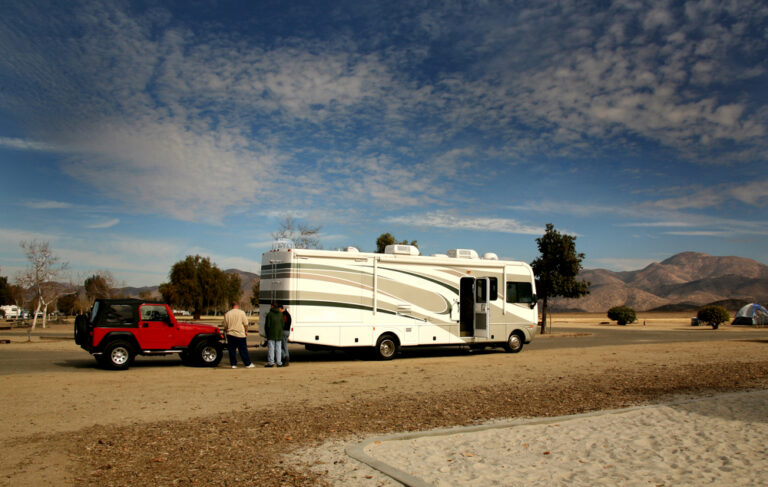 A motorhome towing a red Jeep