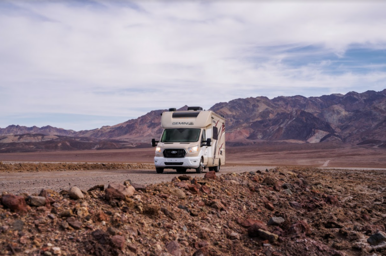 An RV parked in front of red rock mountains