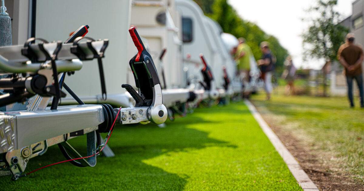 RVs lined up in a lot outside with people walking around