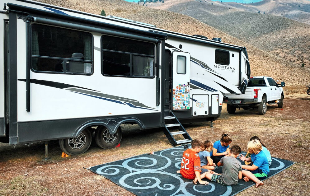 a fifth wheel trailer parked with kids in front