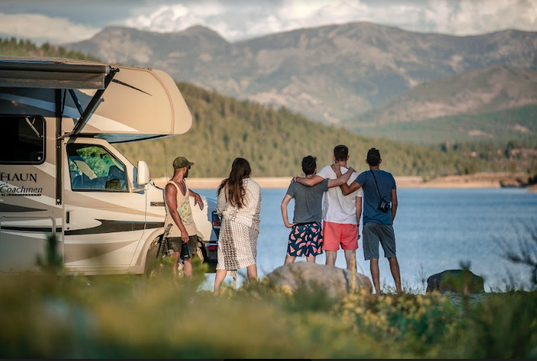 Friends next to an RV by a lake