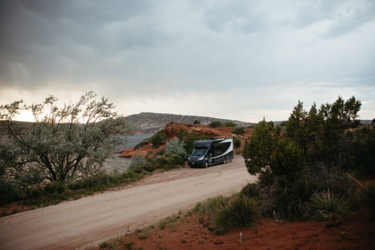 a Class C camper parked by the river