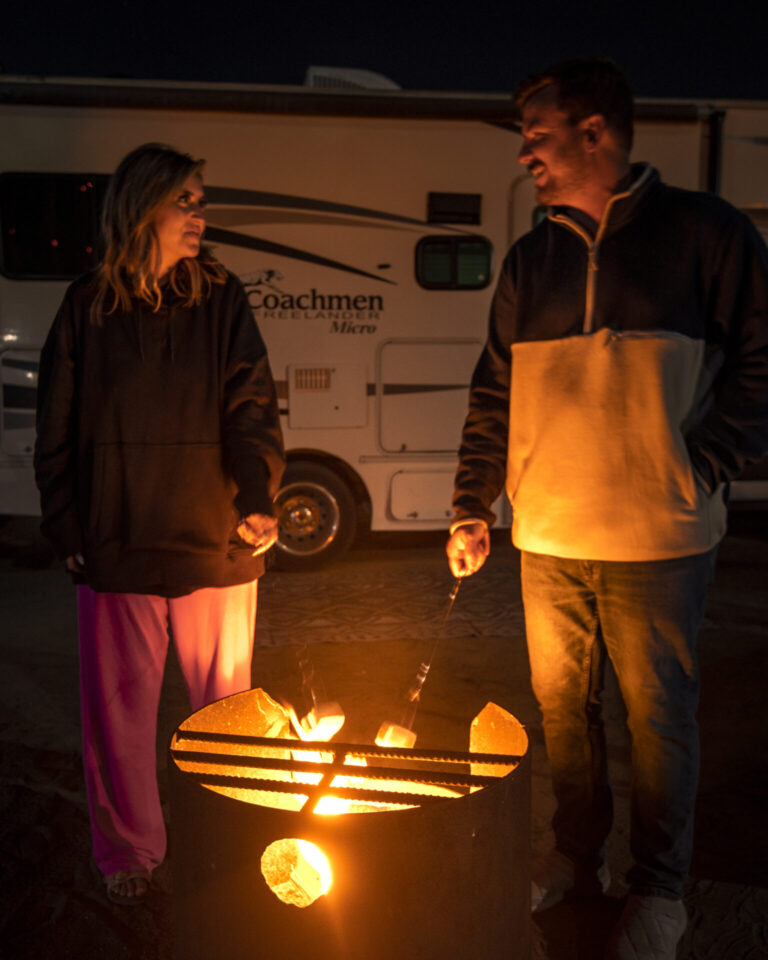 a couple roasting marshmallows over a fire