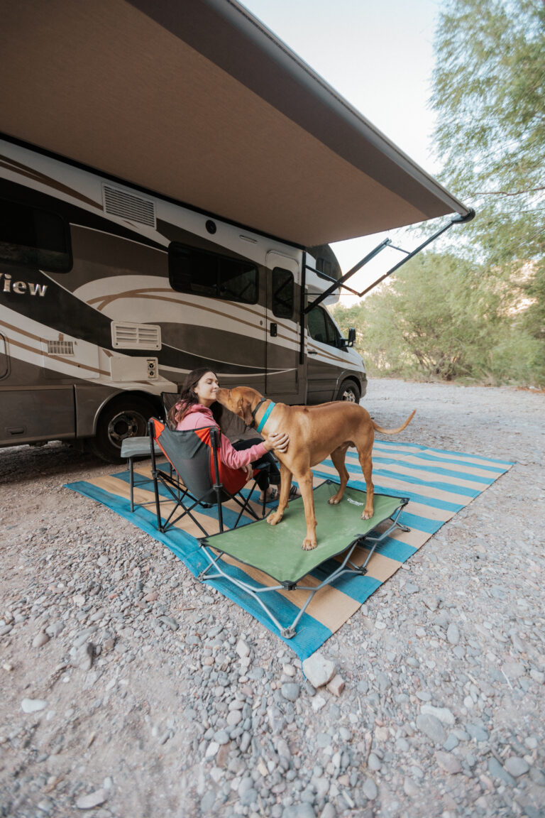 a girl and her dog next to a Class C camper