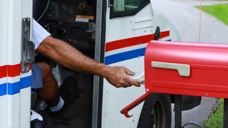 a postal worker putting mail in a mailbox
