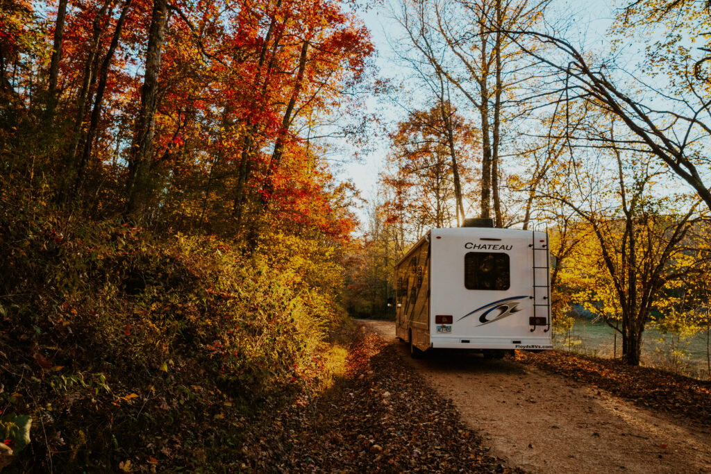 an RV driving down a dirt road in fall