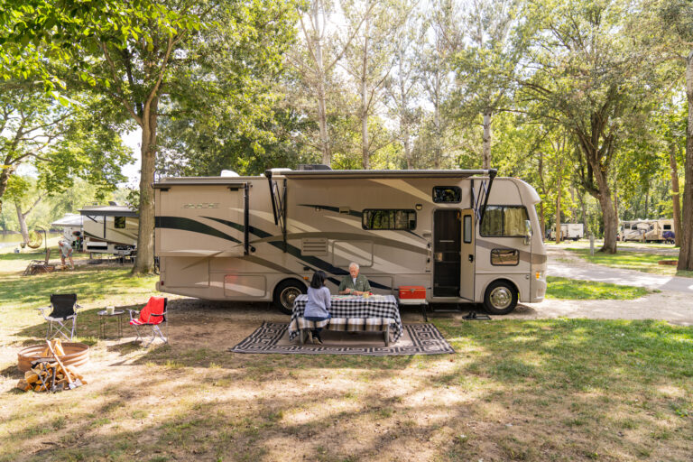 an older couple eating at a picnic table outside their RV