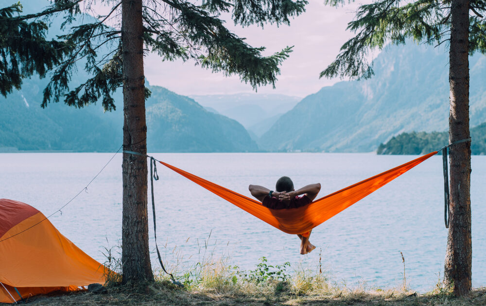 a person relaxing in a hammock next to a lake