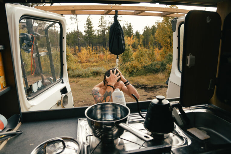 Man taking a pocket shower outside a camper