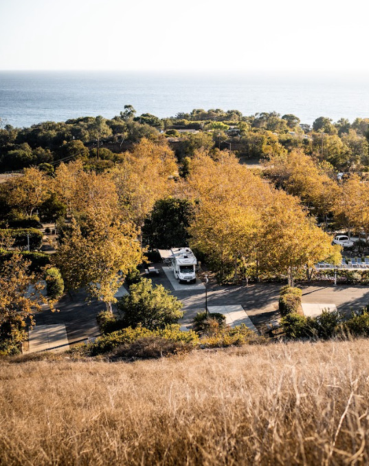 an RV parked in a tree-lined campground