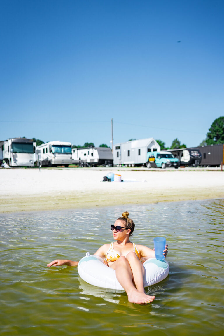 woman in an innertube in river in front of RV