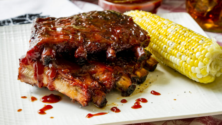 barbeque ribs drenched in sauce with corn