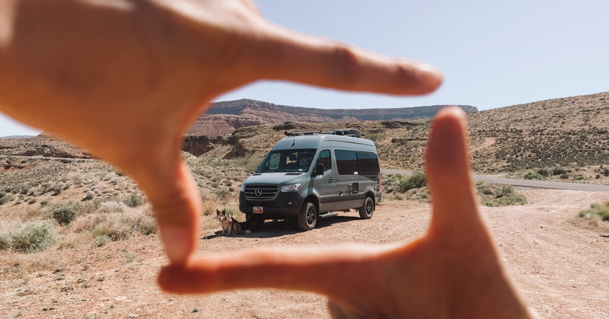 A Class B campervan framed in the distance between someone's fingers