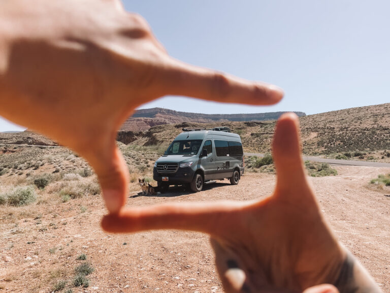 A Class B campervan framed in the distance between someone's fingers