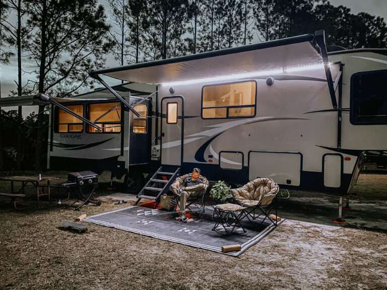 A man relaxing in front of a 5th wheel trailer