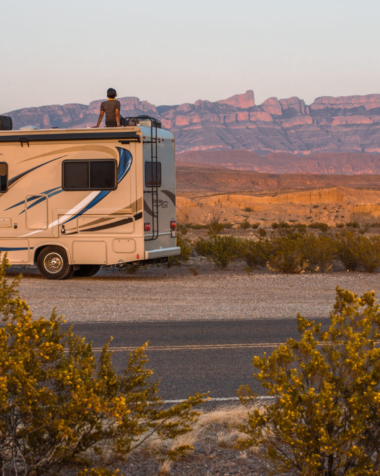 A person sitting on top of their camper watching the sunset