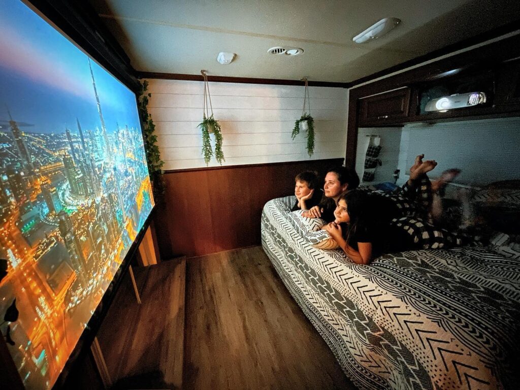 A family watching TV on a large screen in an RV