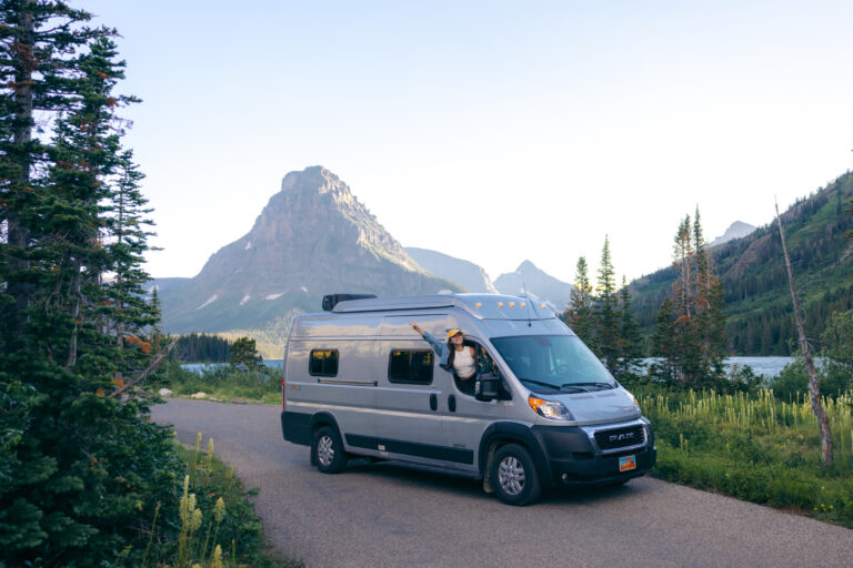 An RV campervan with a person hanging out of the passenger side