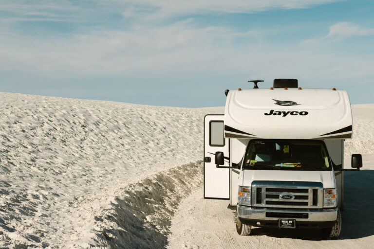 An RV parked next to a sandy desert