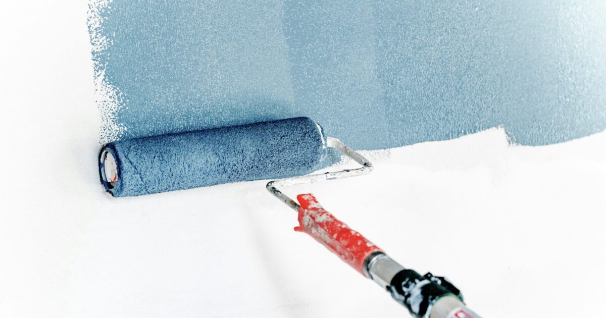 Paint roller painting wall blue. Painting is a great RV renovation idea.