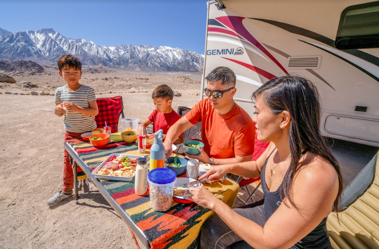 a family picnicking outside their RV