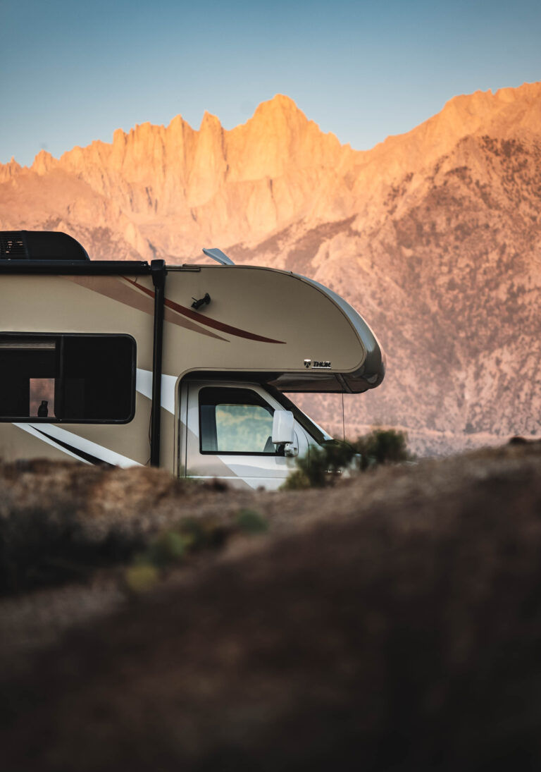 An RV parked in front of red rocks