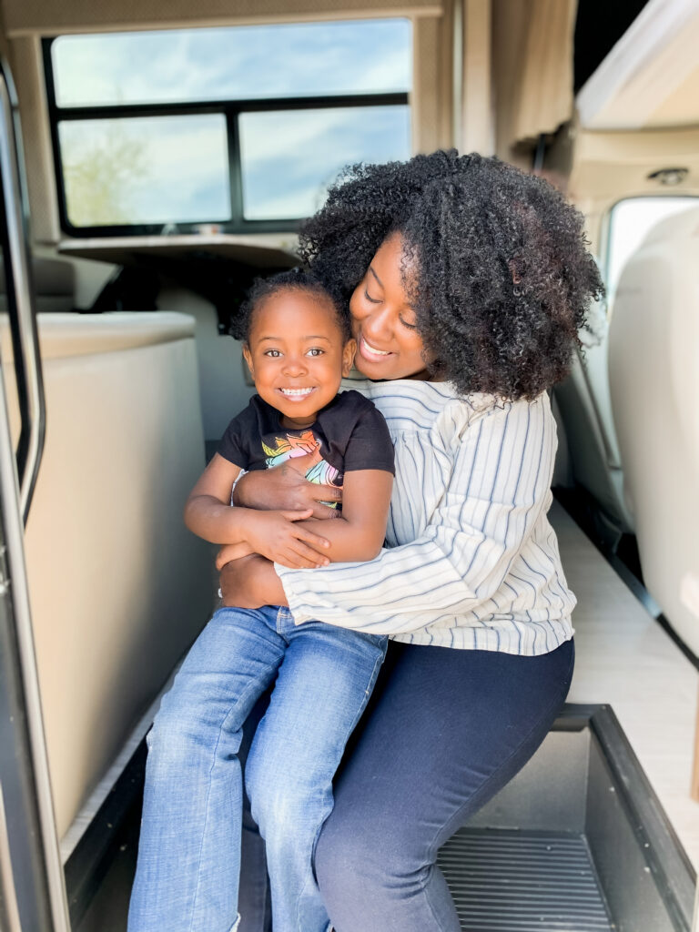 A mom and kid sitting in the doorway of their RV