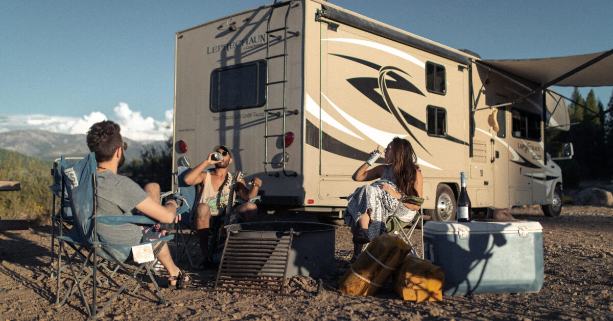 People relaxing and drinking outside an RV