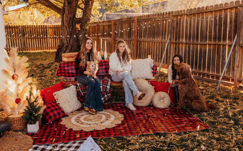 women sitting in a decorated space outside an RV