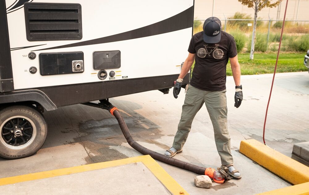 Man stands over RV sewer hose at dump station
