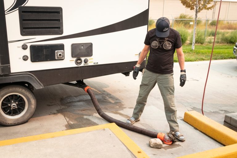 Man stands over RV sewer hose at dump station