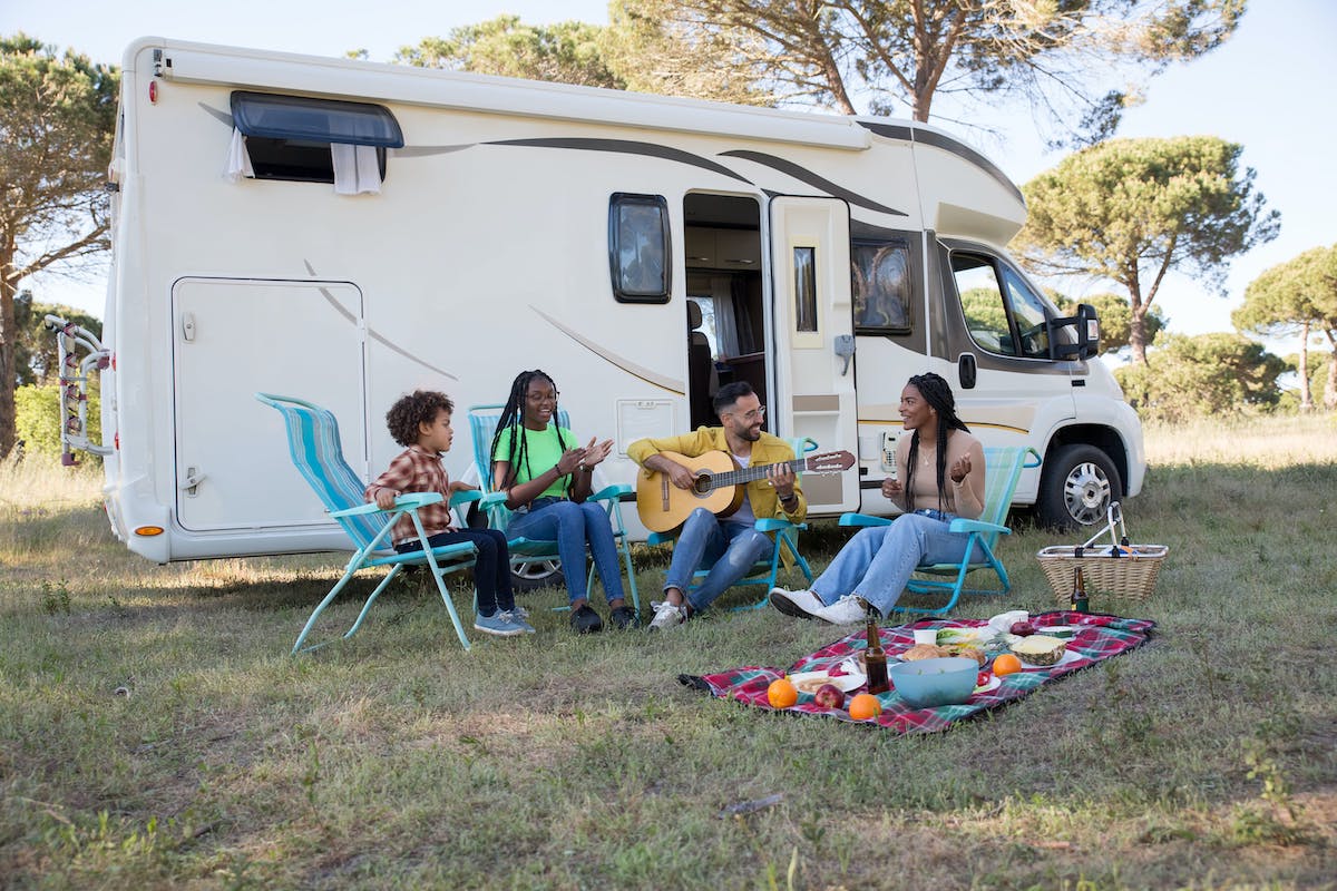 family playing guitar and picnicking beside RV