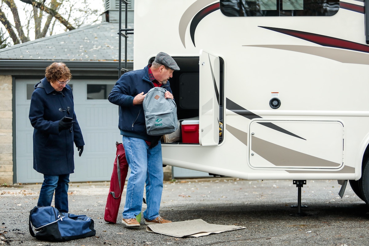 bundled-up couple packing their RV for a trip