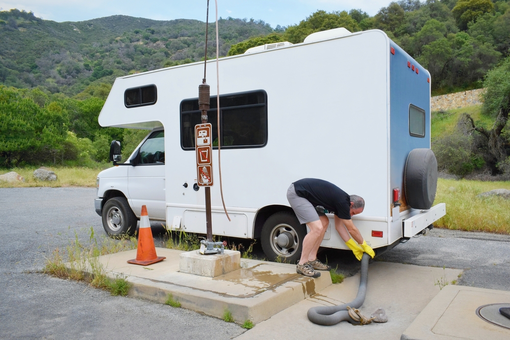 A man using an RV dump station to empty his RV tank