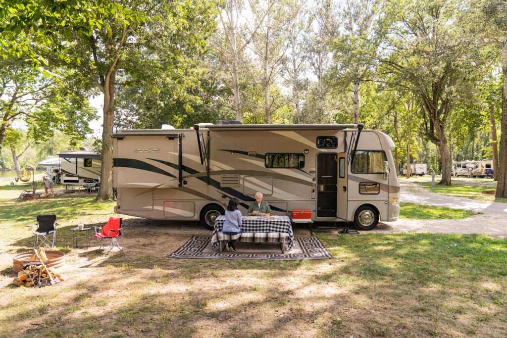 An RV parked in a camping spot next to a picnic table