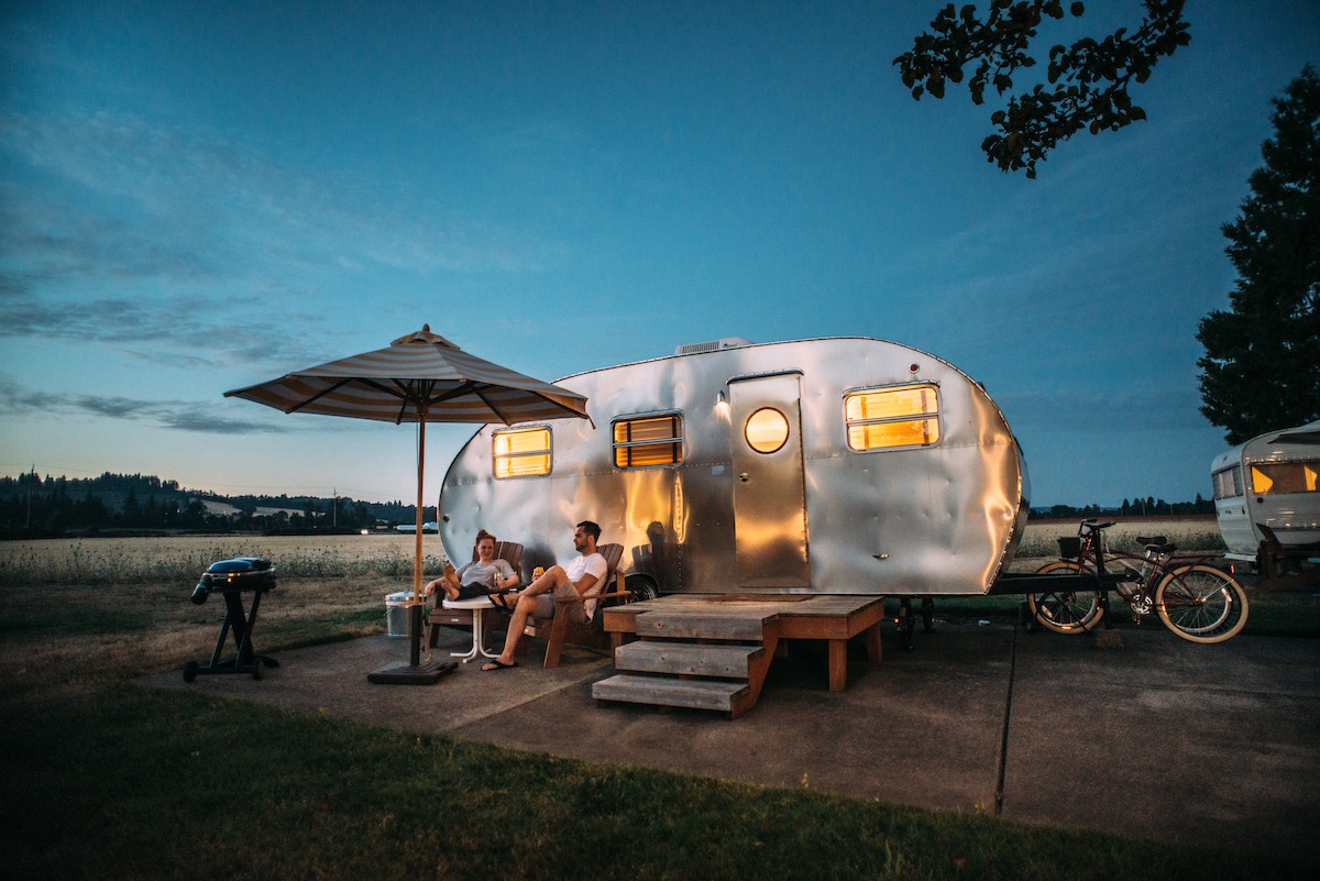 dusk view of couple sitting in chairs with their RV at a campsite