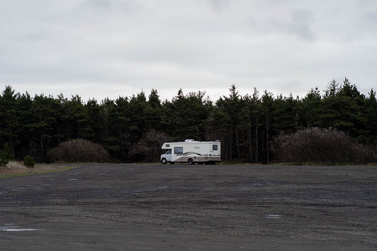 Far away view of RV parked in a lot with trees in background