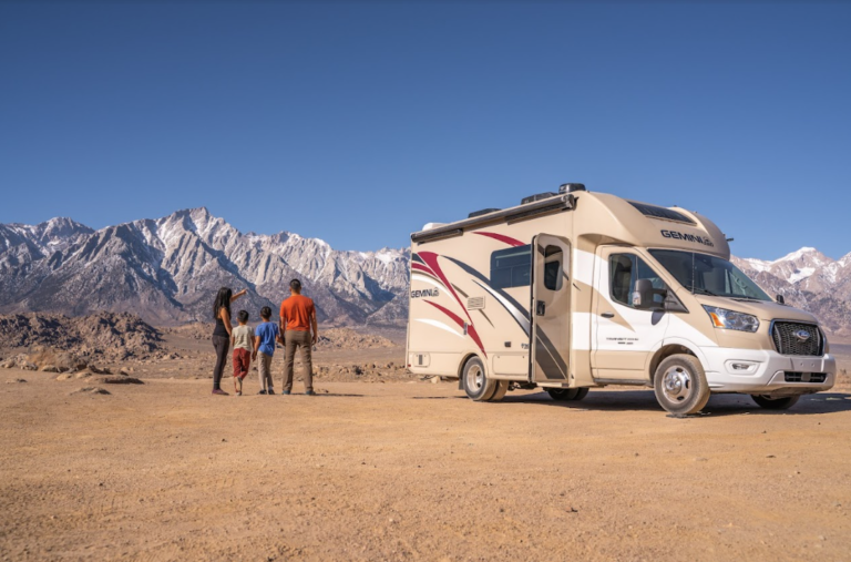 An RV parked before snowcapped mountains