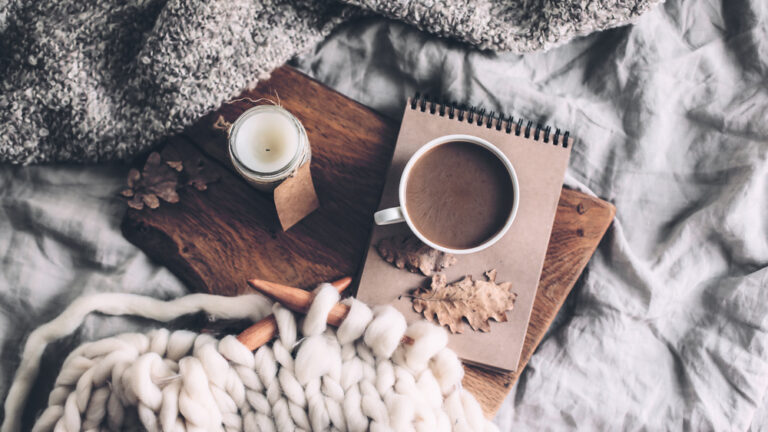 knitting, a cup of coffee, and a candle giving a hygge feel