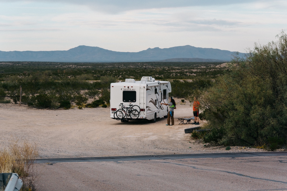 view overlooking 2 people near an RV in an area with mountains