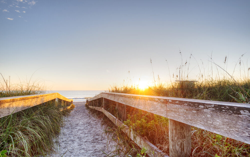 A warm-looking beach landscape visible through a sandy walkway
