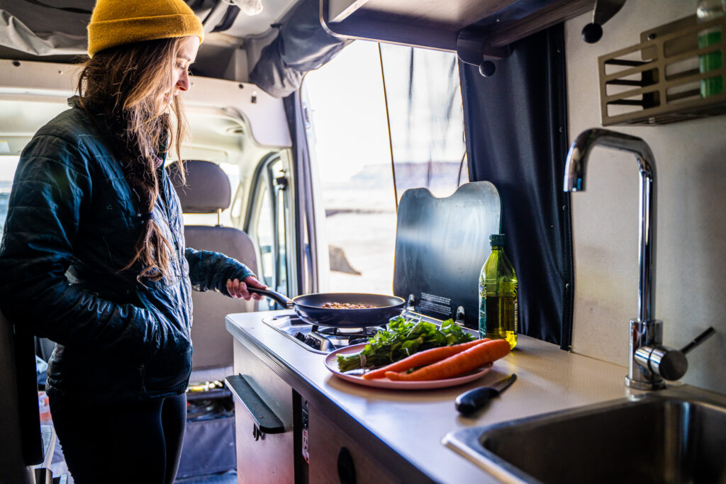 a woman cooking food in a campervan