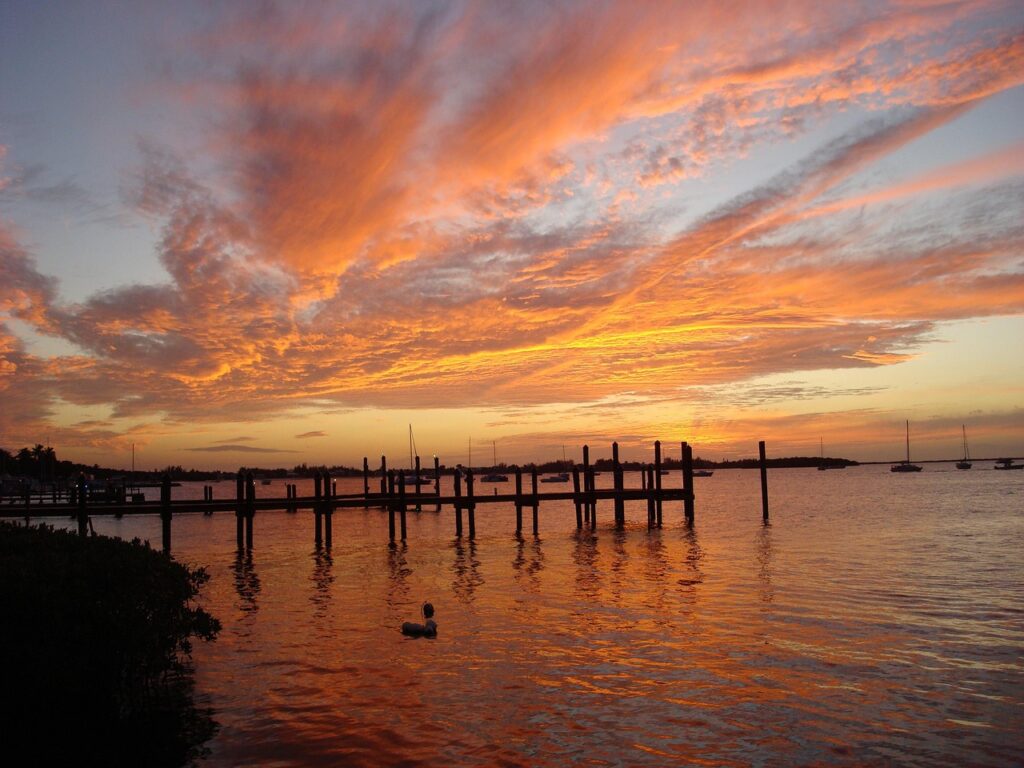 A stunning pink-and-orange sunset over a dock and sailboats in the Florida Keys