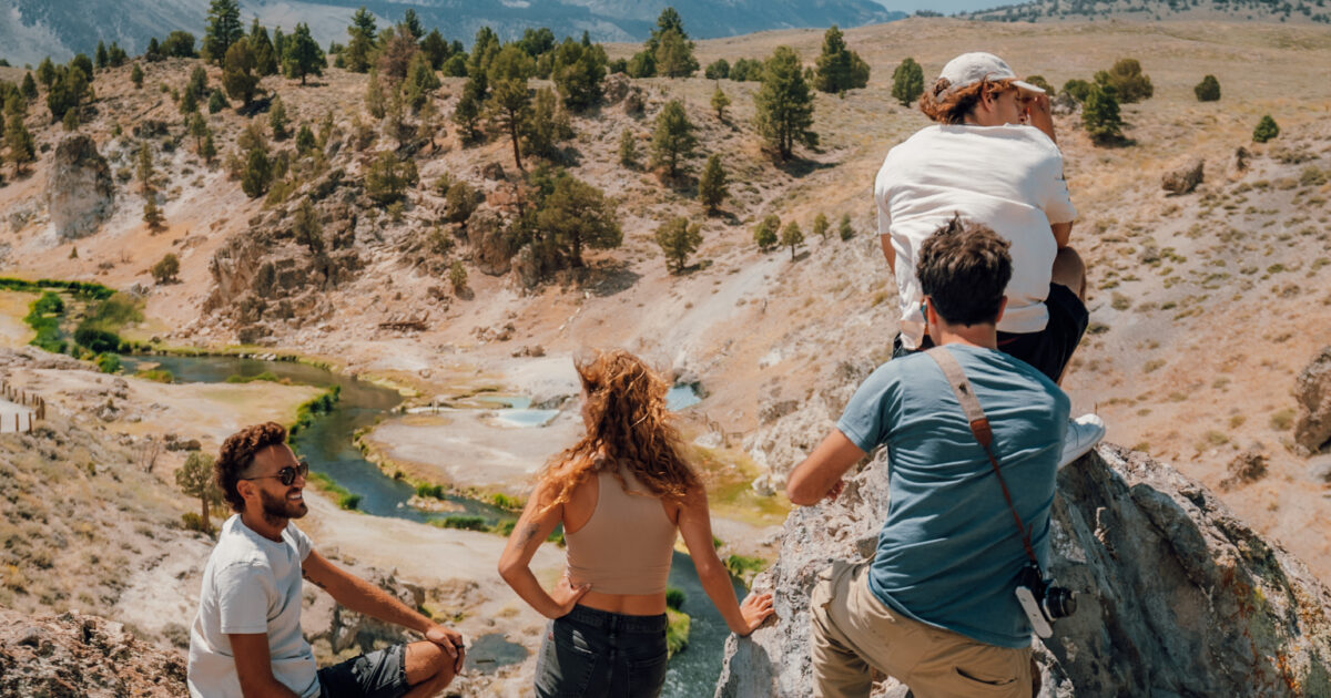 Friends climbing rocks overlooking a stream