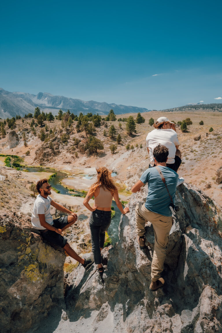 Friends climbing rocks overlooking a stream