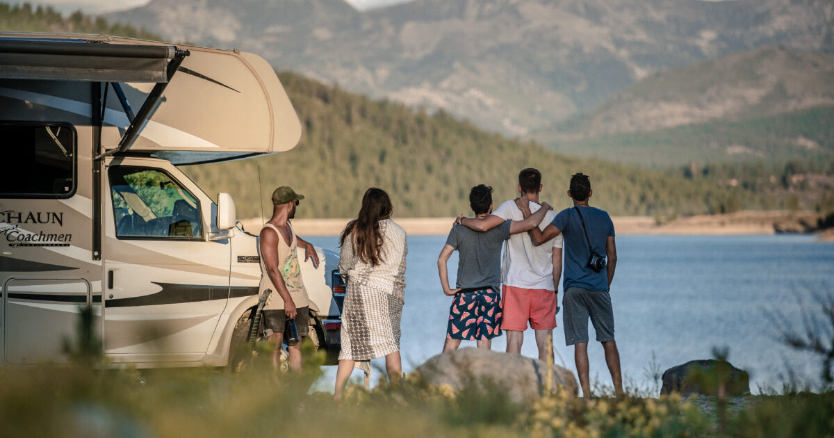 friends looking at lake scenery standing next to an RV