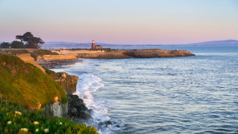 Sunset view of the Pacific Ocean rugged coastline, Santa Cruz, California; Santa Cruz surfing museum in the background